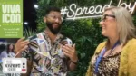 Two people talking and laughing at a conference booth with a neon '#SpreadJoy' sign behind them; left banner reads 'Viva Icon Las Vegas' and a 'The Nonprofit Show' logo.