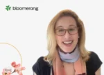 Smiling woman with blonde hair and glasses speaking in a video frame; Bloomerang logo in the top-left corner.