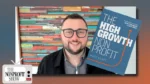 Smiling man with glasses on a video call in front of a colorful wooden backdrop; a blue book titled 'The High Growth Nonprofit' tilts on his right, and a small 'The Nonprofit Show' TV icon sits bottom-left.