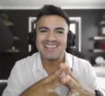 Smiling man in a white shirt wearing a headset during a video call.