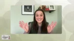 Woman on a video call smiling and waving at the camera in a home office setting.
